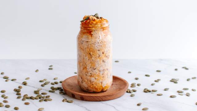 Pumpkin overnight oatmeal in a mason jar with pumpkin seeds, pumpkin puree, and cinnamon.