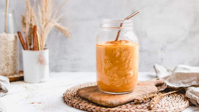 Pumpkin pie smoothie with canned pumpkin, pumpkin spice, almond milk, dates, and oats blended and served in a glass.