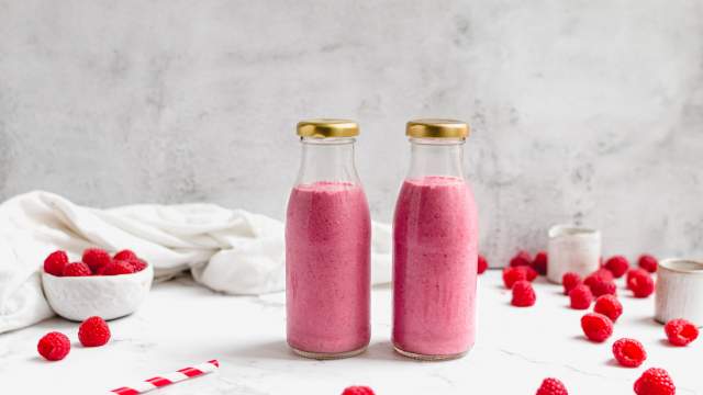 Raspberry chia smoothie with raspberries, chia seeds, almond butter, and almond milk in two glass bottles.