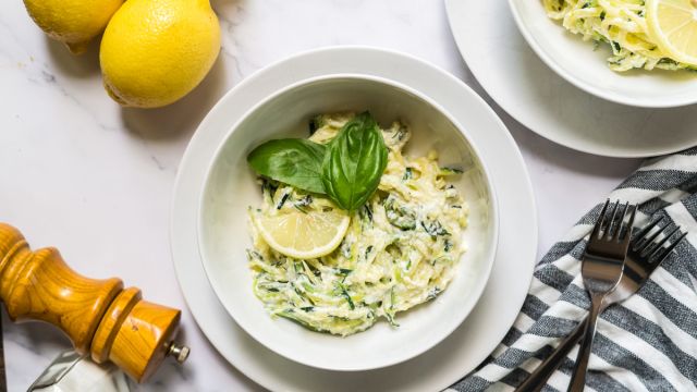 Creamy ricotta zucchini noodles with creamy cheese sauce, lemon, and basil leaves.