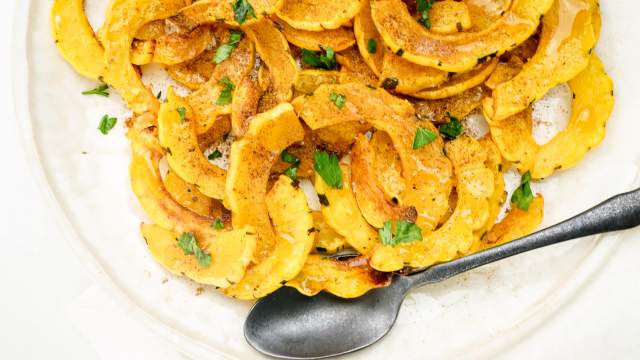 Roasted delicata squash with brown sugar and cinnmon on a white plate.