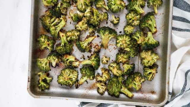 Roasted frozen broccoli on a baking sheet with seasonoing.