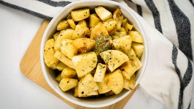 Roasted parsnips with browned edges in a bowl with dried herbs and spices.