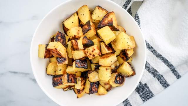 Roasted turnips with olive oil in a white bowl with a blue napkin.