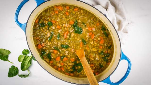 Sausage lentil soup with carrots, turkey sausage, celery, spinach, and brown lentils in a Dutch oven.