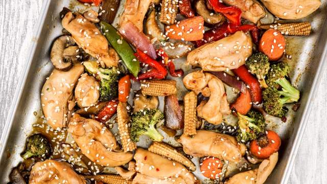 Sheet pan Asian chicken stir fry with chicken breast, peppers, broccoli, and other veggies on a sheet pan.