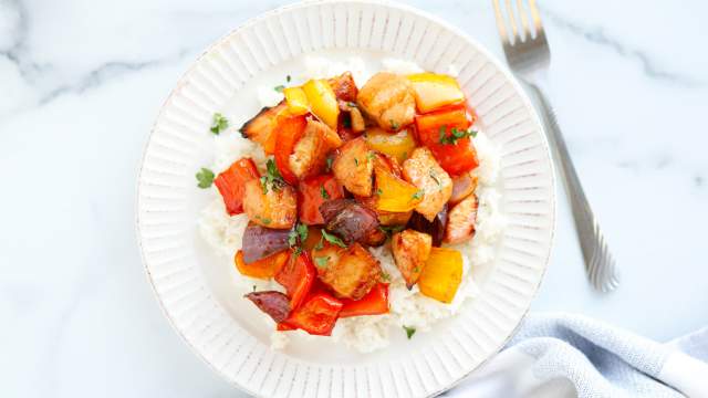 Sheet pan honey Sriracha chicken and vegetables on a white plate with rice.