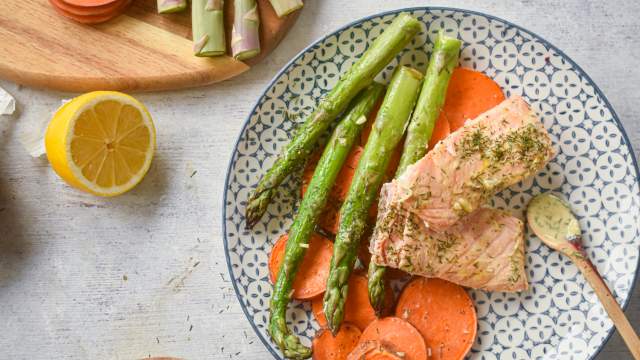 Sheet pan roasted salmon with sweet potatoes and asparagus on a plate with lemon dijon sauce.