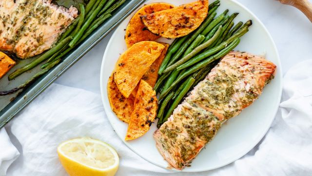 Sheet pan salmon with green beans and butternut squash served with a lemon and mustard sauce on a plate.