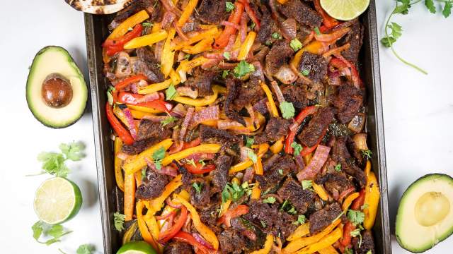 Sheet pan steak fajitas made with homemade fajita seasoning, flank steak, bell peppers, and onions on a sheet pan. 