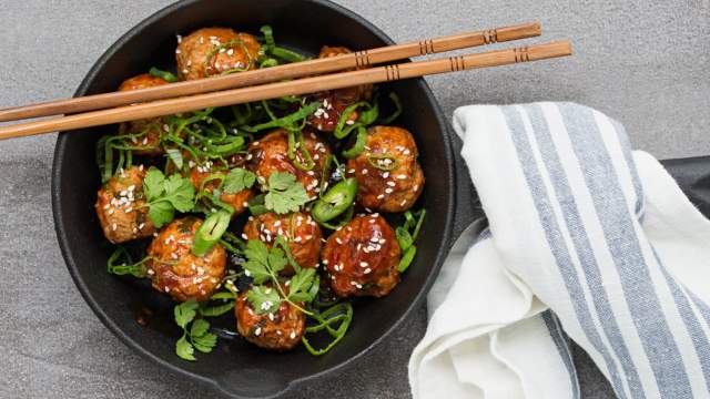 Slow Cooker Asian Meatballs in a skillet with cilantro and green onions on top.