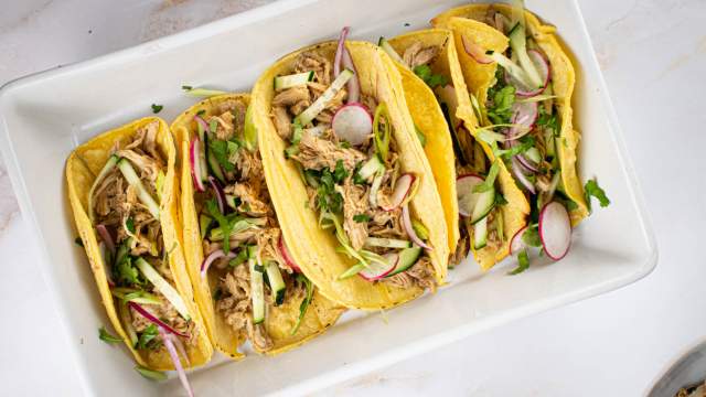 Slow cooker Banh Mi Pork with green onions, cucumbers, radishes, and cilantro in corn tortillas.