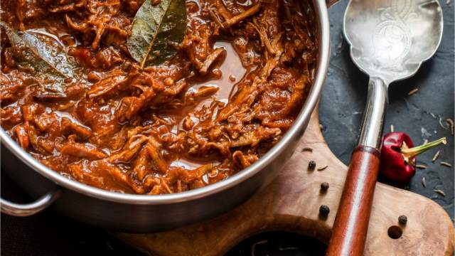 Slow cooker beef rago with shredded beef, tomato sauce, and fresh basil.