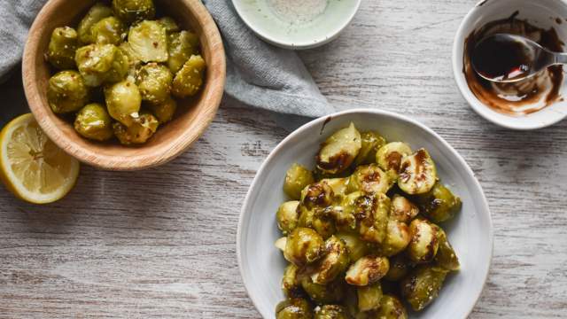 Slow cooker Brussels sprouts in a bowl with Parmesan cheese, lemon, and balsamic glaze.