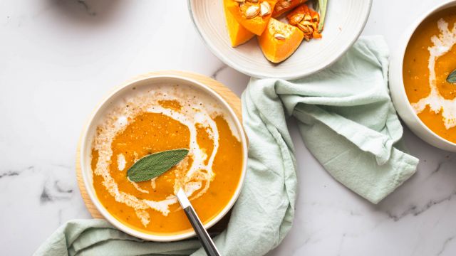 Slow cooker butternut squash soup in two bowls with a sage leaf on top.