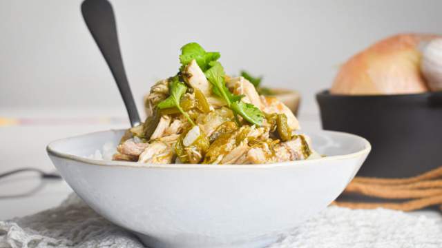 Slow cooker chicken chile verde with tomatillo salsa in a bowl with rice and cilantro.