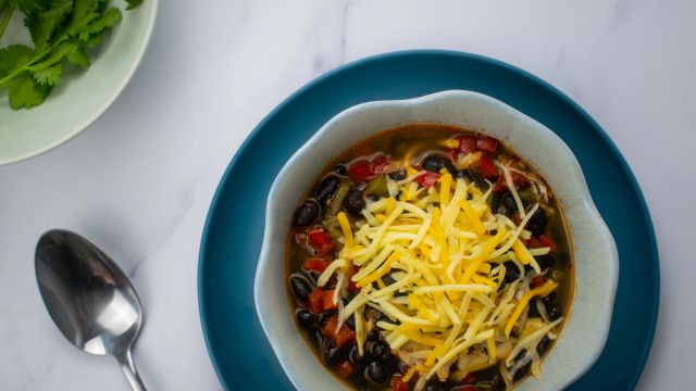 Slow Cooker Chicken Enchilada Soup with shredded cheese and cilantro.