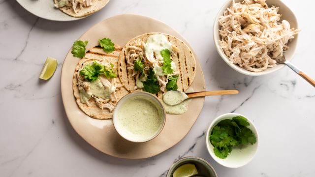 Slow cooker jalapeno chicken tacos with cilantro and Greek yogurt sauce served on corn tortillas.