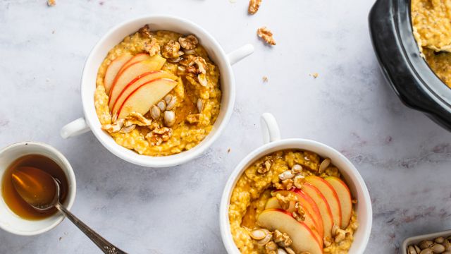 Slow cooker steel cut oatmeal with pumpkin pie spices on a plate with sliced banana.