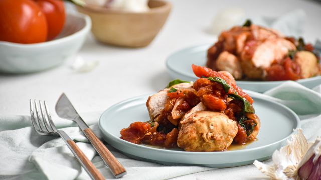 Slow cooker tomato balsamic chicken with spinach served on two plates.