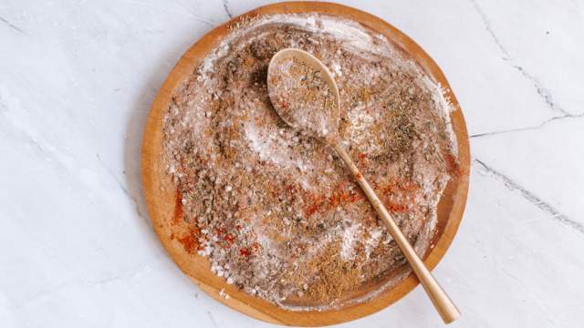 Steak seasoning with kosher salt, pepper, paprika, garlic powder, onion powder, and herbs on a wooden plate.