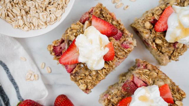 Strawberry banana baked oatmeal cut into sqaures with yogurt and honey on top.