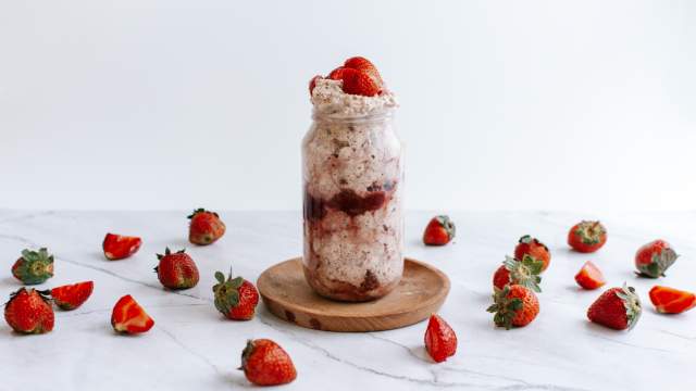 Strawberry overnight oatmeal with rolled oats and chia seeds in a mason jar with fresh strawberries and cream.