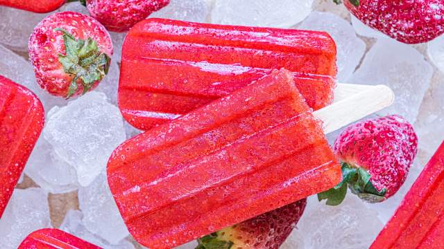 Strawberry popsicles made with fresh strawberries and honey served on a plate with ice.