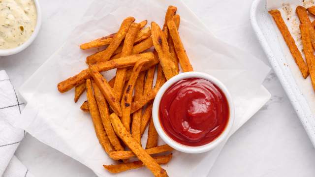 Baked sweet potato fries with a crispy exterior on a plate with ketchup.