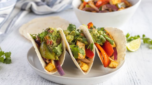 Tofu fajitas with extra firm tofu, red bell peppers, green bell peppers, and red onions cooked in spices served in flour tortillas with guacamole.