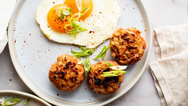 Turkey breakfast sausage served on a plate with sunny side ip eggs and green onions.