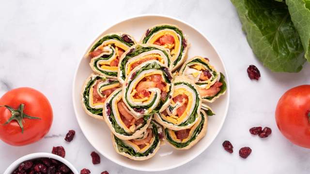 Turkey pinwheels with cream cheese, dried cranberries, cheddar cheese, lettuce, and tomatoes wrapped in a tortilla and sliced into pinwheels.