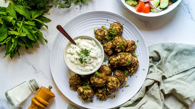 Turkish kofte meatballs made with ground lamb, beef, herbs, and spices served with yogurt sauce and salad.