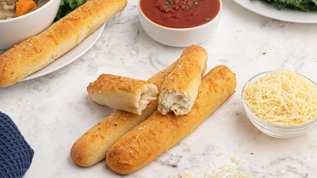 Two ingredient dough breadsticks made with Greek yogurt and self rising flour on a plate with marinara sauce on the side.