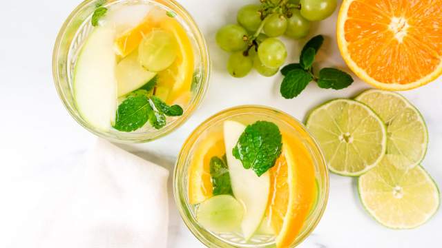 Vinho Verde white sangria with grapes, green apples, and orange in two glasses with fruit on the side.